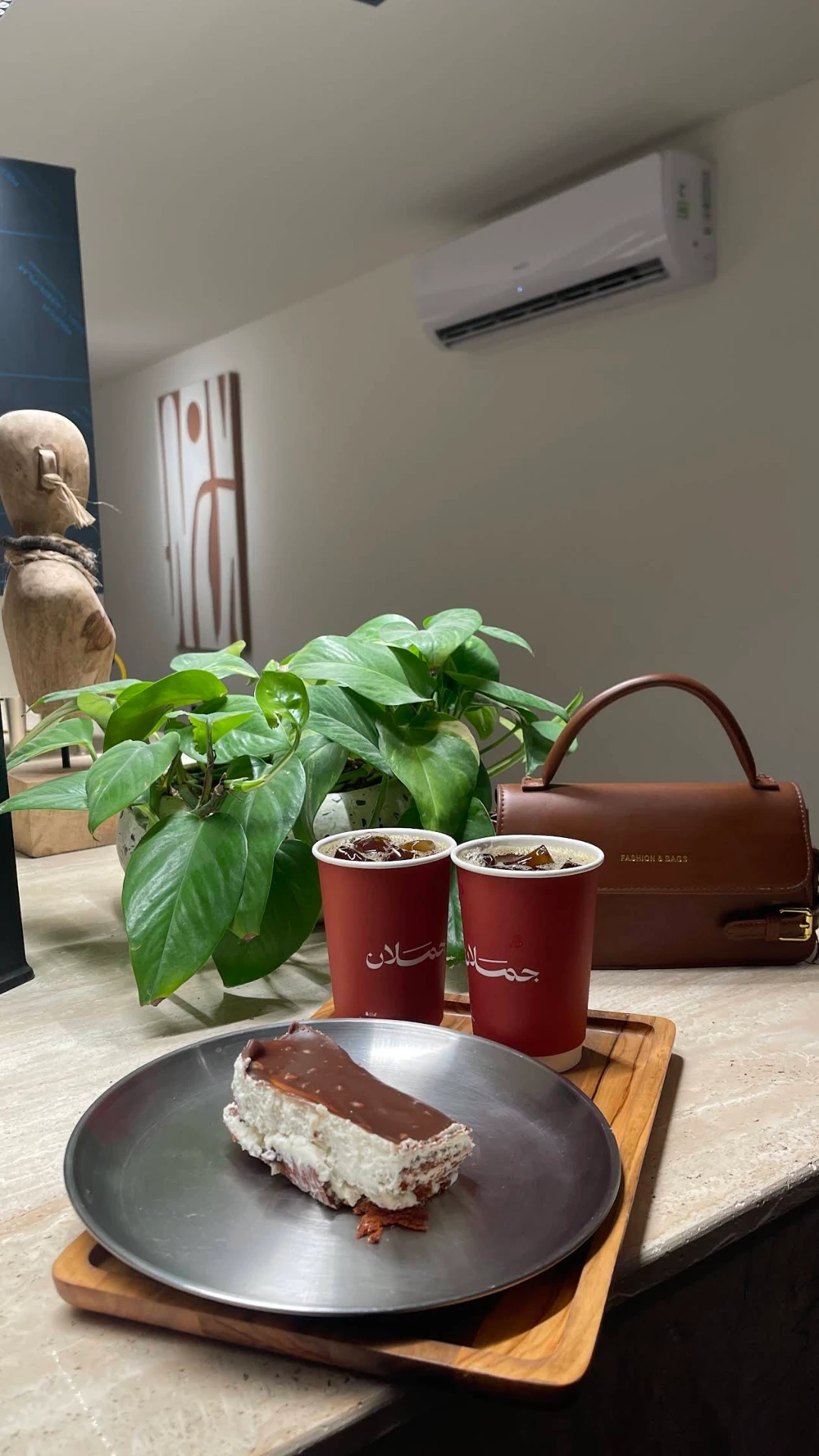 كوبان من جملان وقطعة كيك على صينية معدنية بجانب نبتة